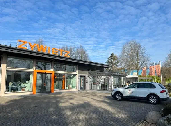 Das moderne ZYWITZ-Firmengebäude mit Glasfassade und Firmenfahrzeug im Vordergrund.