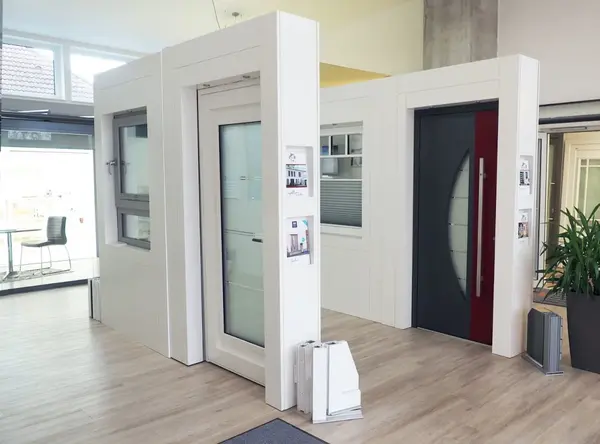 Moderne Ausstellung von Haustüren und Fenstern in einem hellen Showroom mit Holzfußboden.