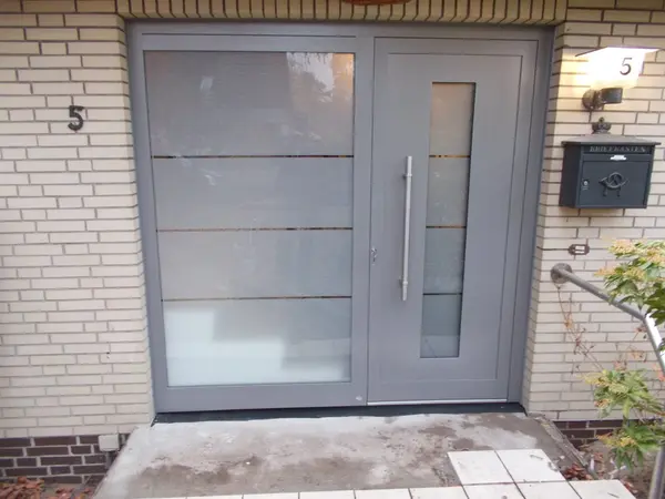 Moderne Haustür aus Aluminium mit Seitenteil und Glaselementen in einem Eingangsbereich.
