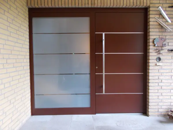 Moderne Haustür aus braunem Metall mit seitlichem Glaselement und klaren Linien.