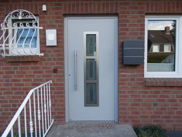 Moderne Haustür aus Aluminium mit Glaseinsätzen in einer roten Klinkerfassade.