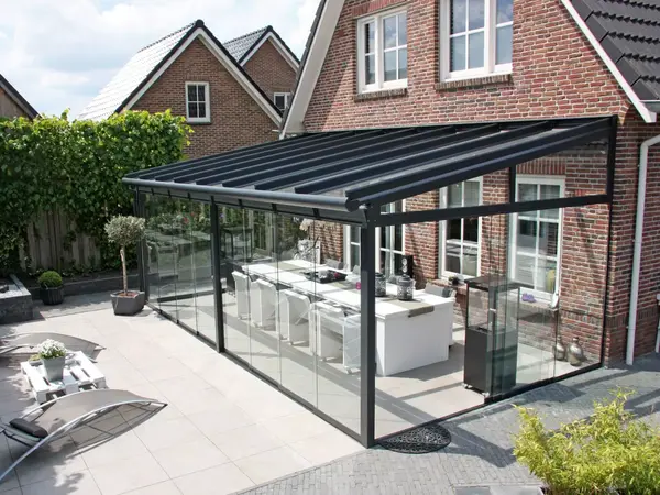 Moderne Terrassenüberdachung aus Glas am Einfamilienhaus mit Garten und Sitzbereich.