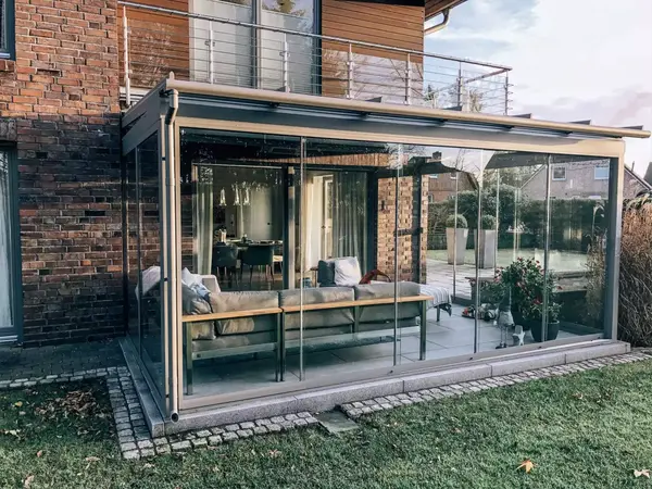 Moderner Wintergarten mit Glaswänden an einem Einfamilienhaus mit Garten und Terrasse.